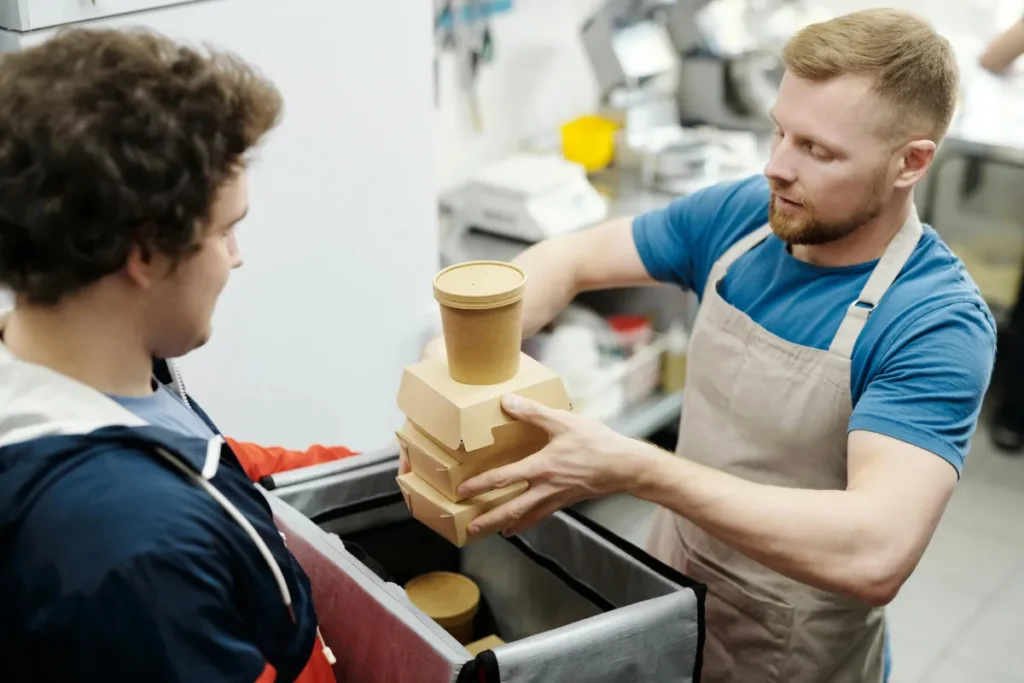 Pekerja pengiriman makanan mengemas wadah makanan ke dalam tas di dapur restoran