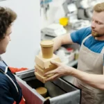 Pekerja pengiriman makanan mengemas wadah makanan ke dalam tas di dapur restoran