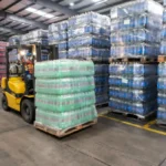 Operator forklift memindahkan tumpukan pallet di gudang logistik yang sibuk sebagai ilustrasi fungsi pallet dalam pergudangan